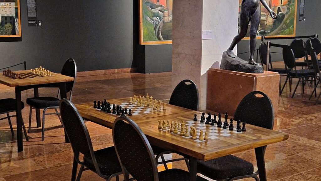 Professional modular Bughouse chess tables by ChessboArt, set up for a tournament in the Hungarian National Gallery, surrounded by works of art.